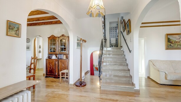 Ein geräumiger Innenraum mit Treppe, Holzbalken und einem Essbereich.