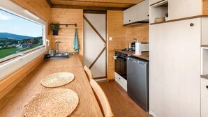A compact kitchen with wooden walls, a built-in oven, and a dishwasher. - Lovely home in Niedzwiedz with sauna (Niedzwiedz)