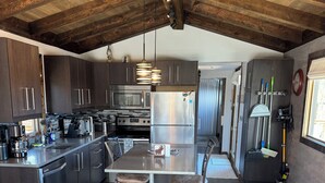 Uma cozinha moderna com armários de madeira escura, eletrodomésticos de aço inoxidável e uma ilha central com banquetas.