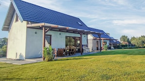 A modern house with a sloped roof, a covered patio with outdoor furniture, and a well-maintained lawn. - 3 bedroom stunning home in Odargowo (Odargowo)
