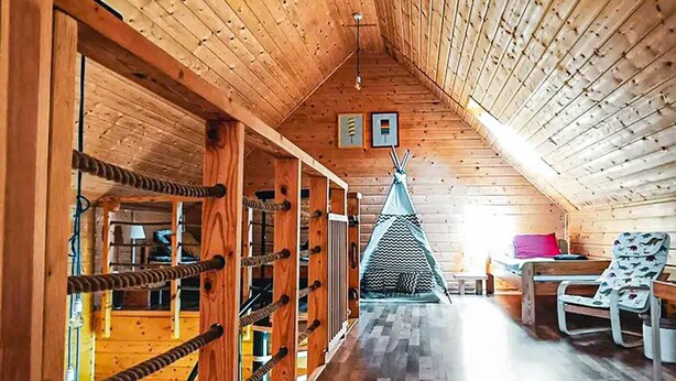 A wooden interior with a high ceiling, a visible window, a bed, and a chair. - 3 bedroom stunning home in Odargowo (Odargowo)