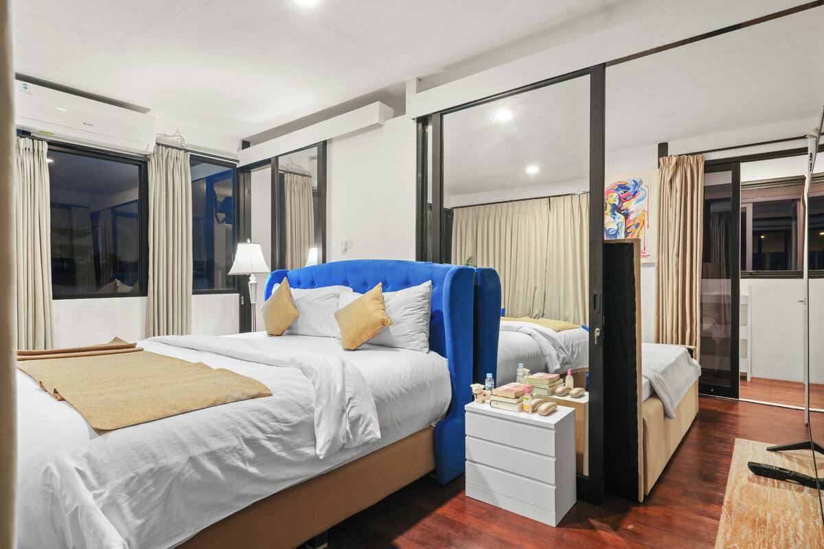 A hotel room with a large bed, a bedside table, a desk, and a window with curtains.