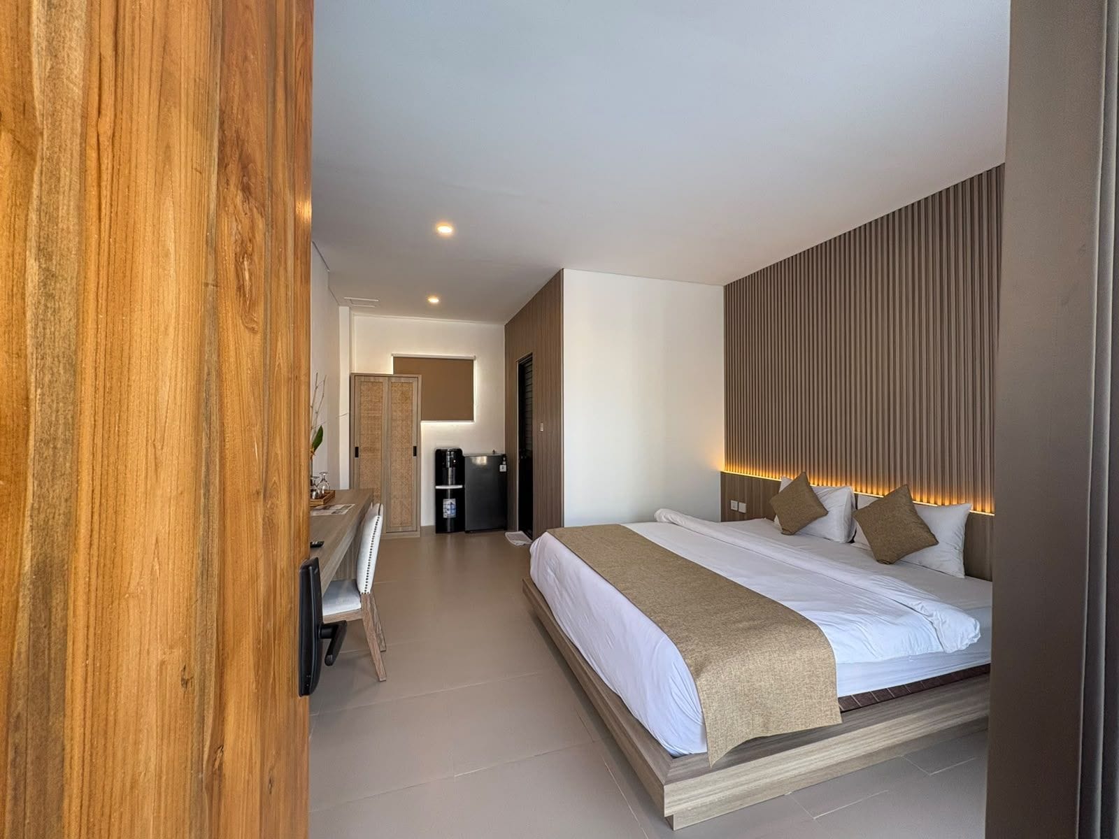 Una habitación de hotel moderna con una cama grande, un escritorio y un minibar.