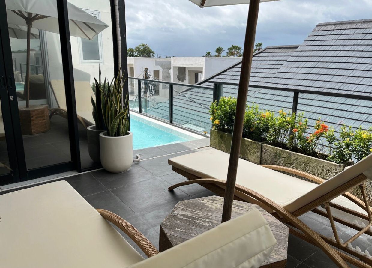 A rooftop terrace with a pool, lounge chairs, and potted plants.