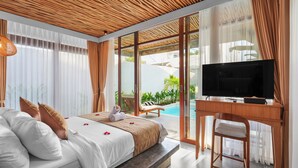Una camera da letto con un letto, una TV, una scrivania e vista su una piscina.