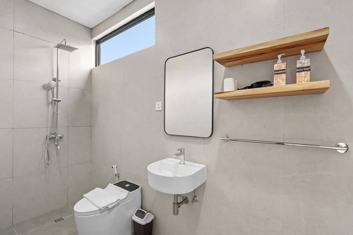 A modern bathroom with a shower, toilet, sink, and a mirror.