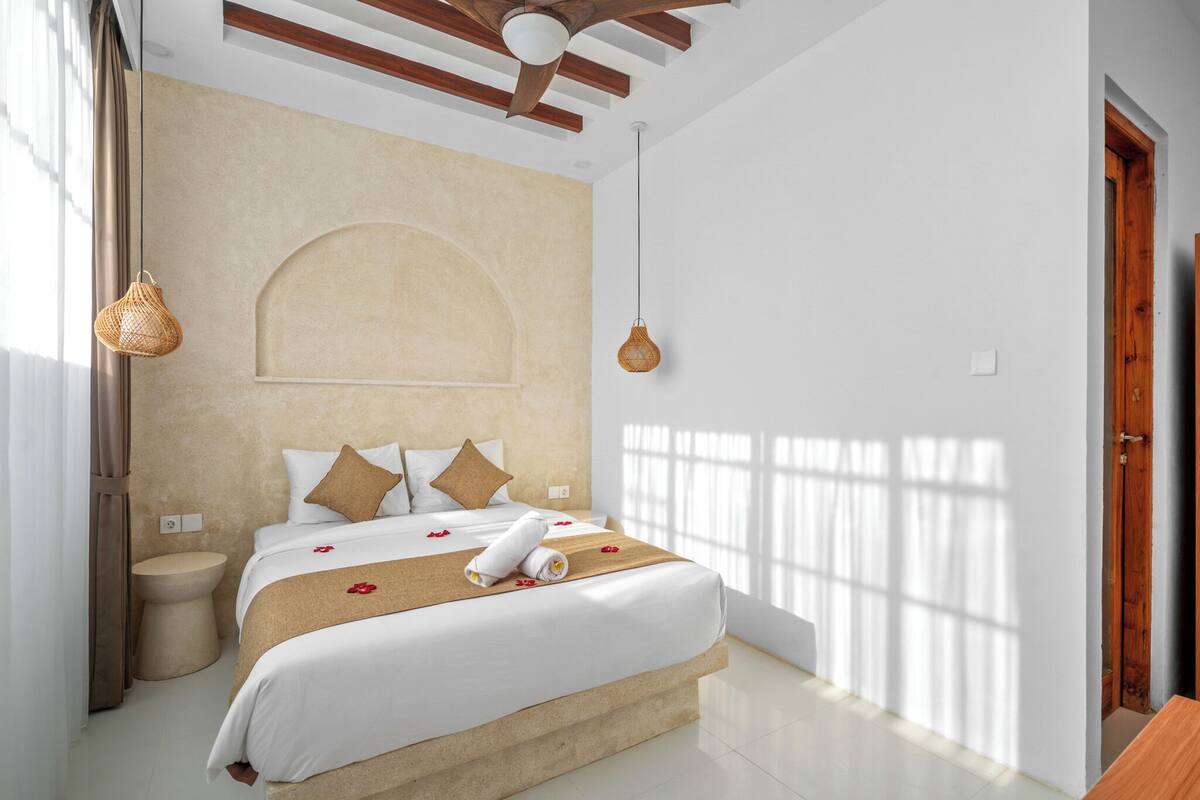 A hotel room with a bed, bedside table, and a ceiling fan.