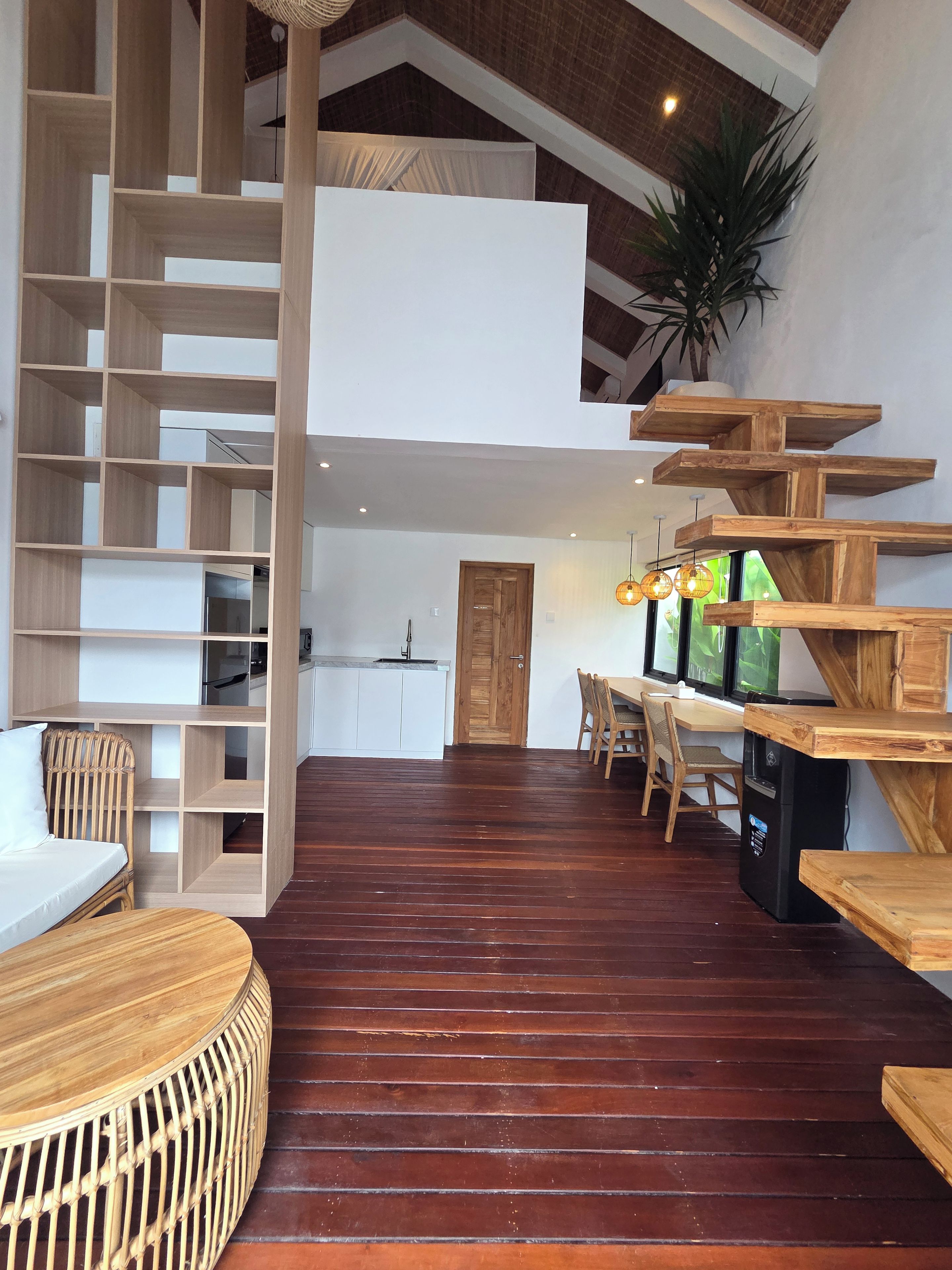 A modern interior with a wooden staircase, a dining area, and a kitchen.