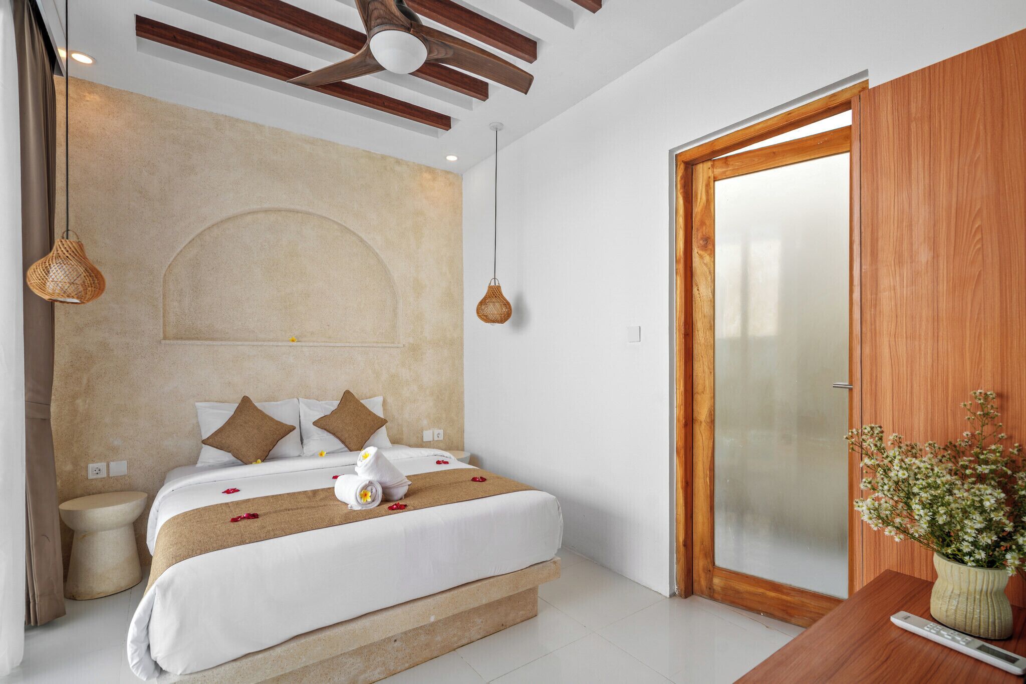 A hotel room with a bed, bedside table, and a wooden door.