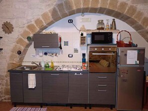 Una cucina con arco in pietra, forno a incasso, microonde e frigorifero.