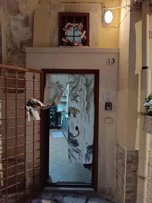 Una stanza con una porta decorata con motivo tigrato, una targa con il numero 13 e una piccola finestra con cornice ornamentale.