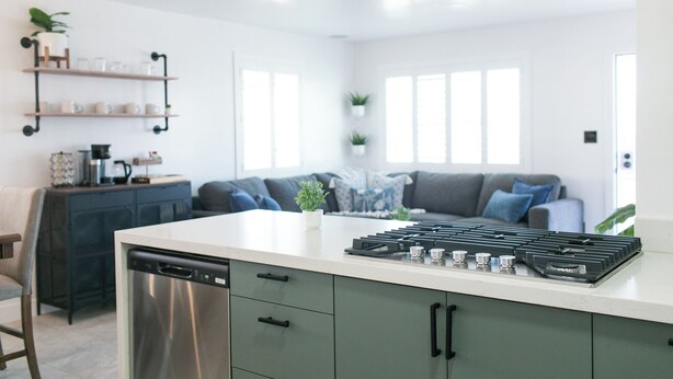 A modern kitchen with a dishwasher, stove, and a built-in oven. There is a grey sofa and a coffee machine in the background. - Charming 3-bedroom house in peaceful Tempe minutes from the Aiport (Tempe)