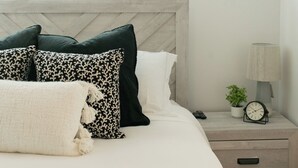 A bedroom with a bed, pillows, a bedside table with a lamp, a clock, and a potted plant. - Charming 3-bedroom house in peaceful Tempe minutes from the Aiport (Tempe)