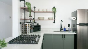 A modern kitchen with a gas stove, a microwave, a sink, and a refrigerator. There are shelves with dishes and plants, and a coffee machine. - Charming 3-bedroom house in peaceful Tempe minutes from the Aiport (Tempe)