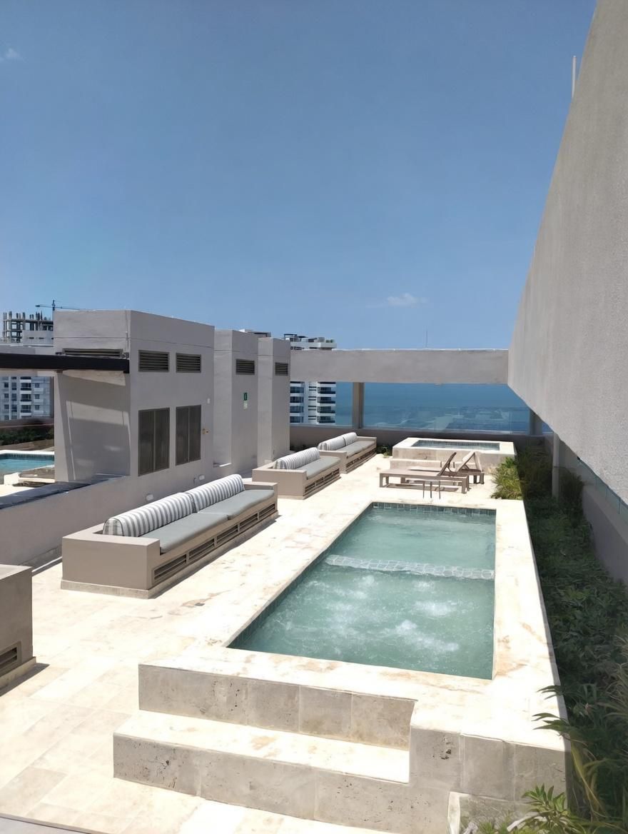 Área de piscina no terraço com assentos e vista para o oceano.