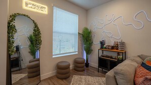 A modern living room with a large mirror, round ottomans, a potted plant, a wooden coffee table, and a neon sign on the wall. - Modern Townhome 10 min to Downtown + Airport (Salt Lake City)