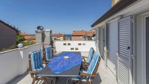 A balcony with a table and chairs, a view of the sea, and a building with shutters. - Holiday apartment with Wi-Fi and balcony (Dajla)