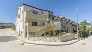 A two-story residential building with a stone facade, a balcony on the upper floor, and a small garden area. - Holiday apartment with Wi-Fi and balcony (Dajla)