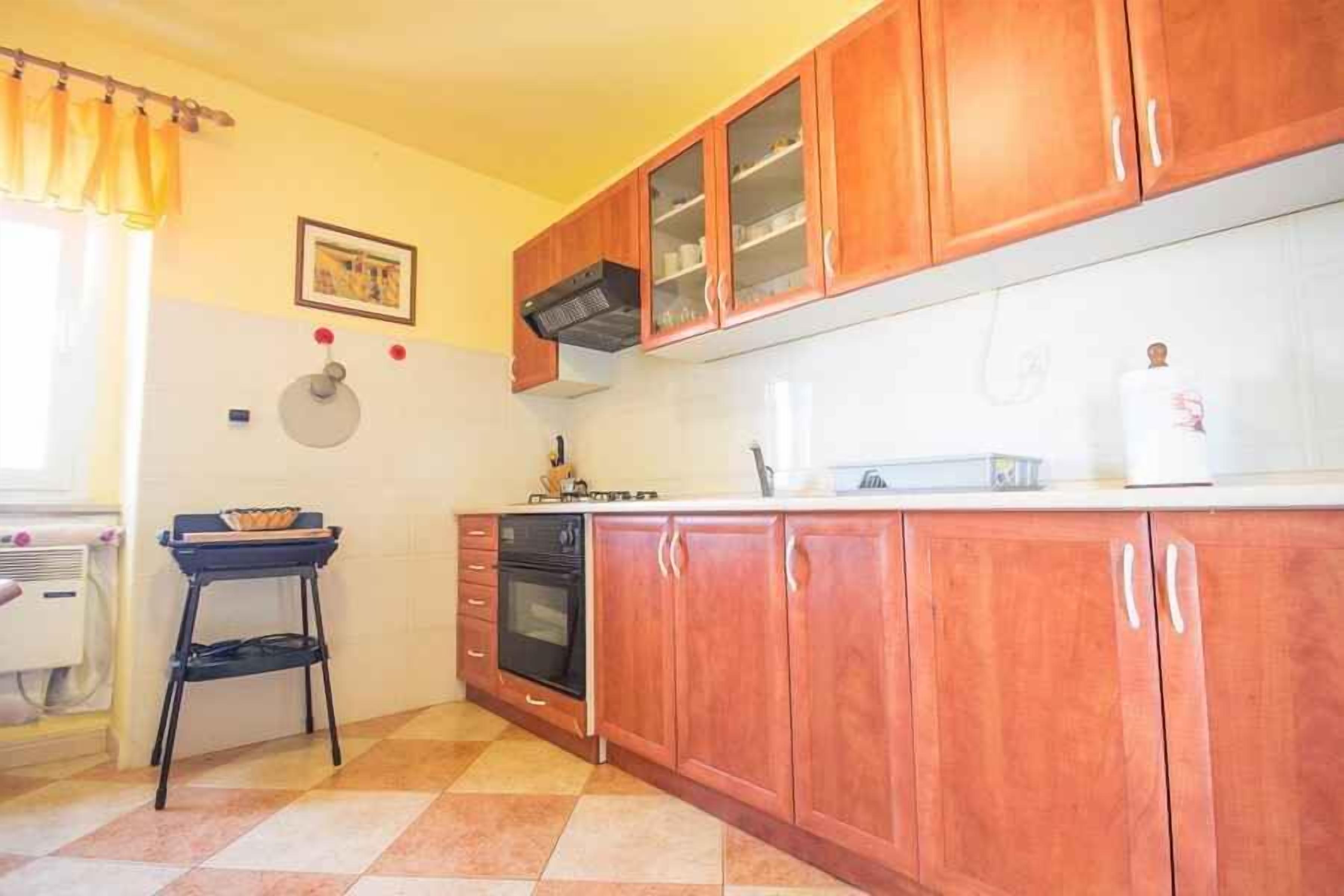 A kitchen with wooden cabinets, a black stove, and a small black table.