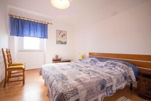A bedroom with a bed, a chair, a window with a curtain, a bedside table, and a wall with a picture. - Holiday Apartment Lovely Apartment Bencic with Balcony and Sea View (Novigrad)