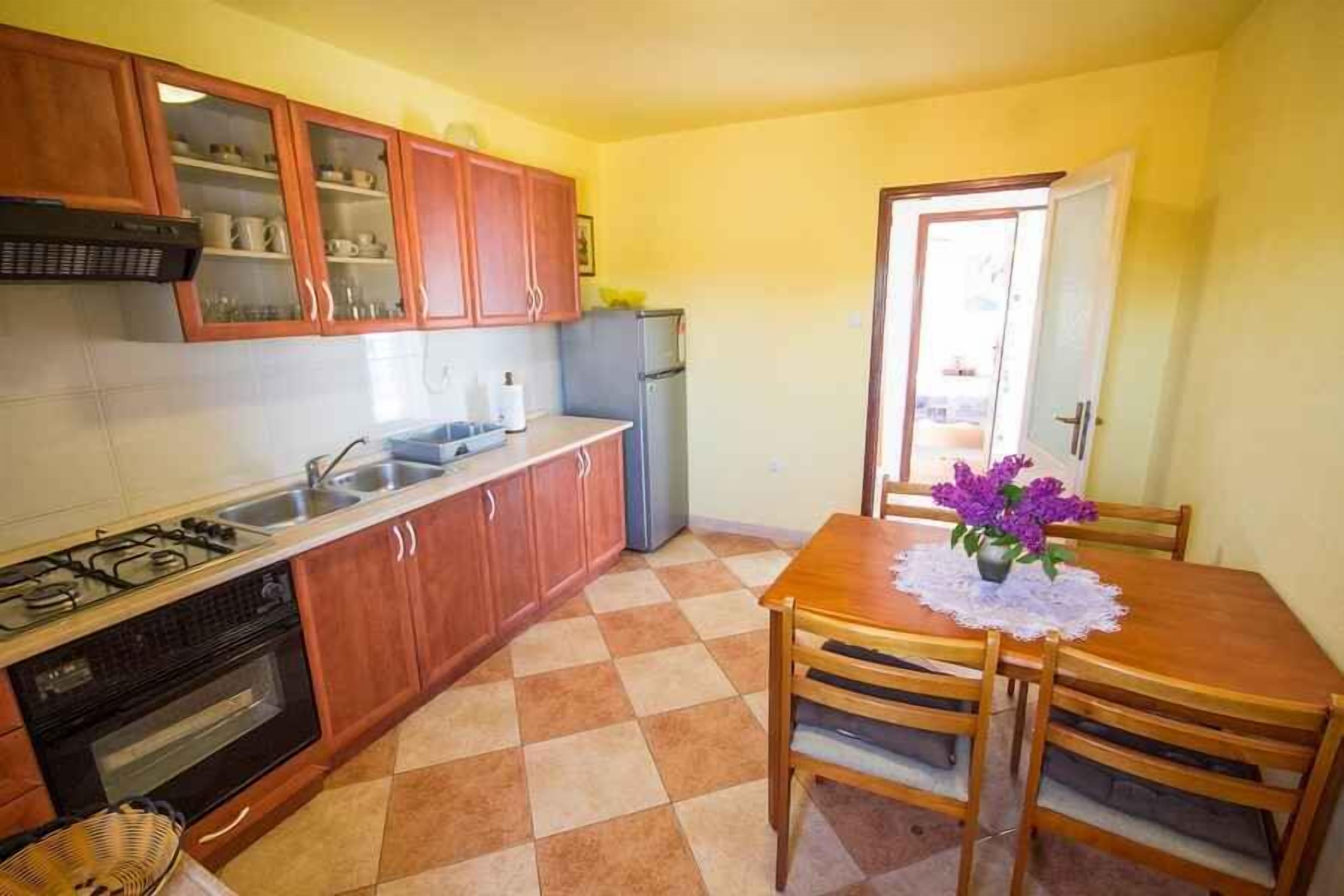 A compact kitchen with wooden cabinets, a gas stove, a sink, and a refrigerator.