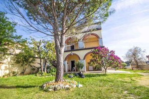 A two-story building with a garden in front, a tree, and a purple flowering bush. - Holiday Apartment Lovely Apartment Bencic with Balcony and Sea View (Novigrad)