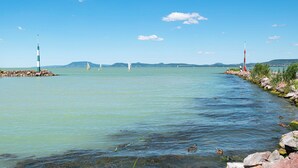 A calm river with clear water, surrounded by rocky shores and distant mountains. - Studio with air conditioning and Wi-Fi near the water (Balatonlelle)