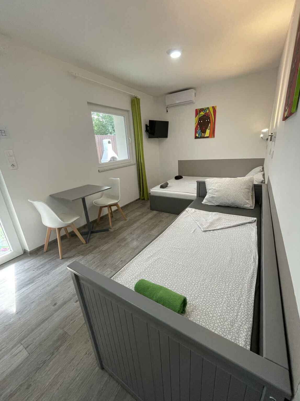 A modern hotel room with a bed, a desk, a chair, a TV, and a window.