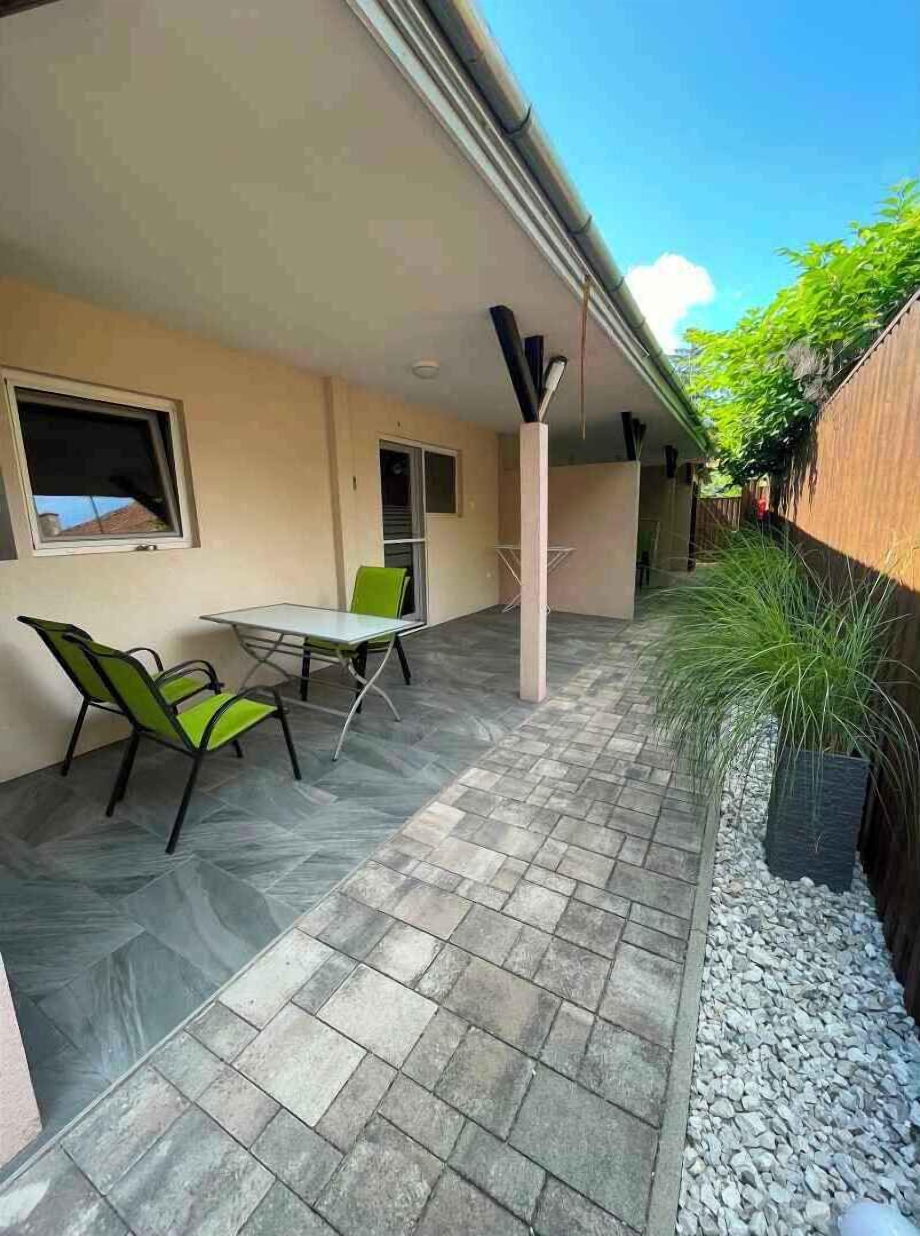 A patio with a table and chairs, a window, and a wall with a plant.