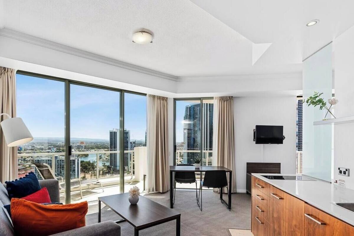 A modern hotel room with a large balcony, a dining area, and a kitchenette.