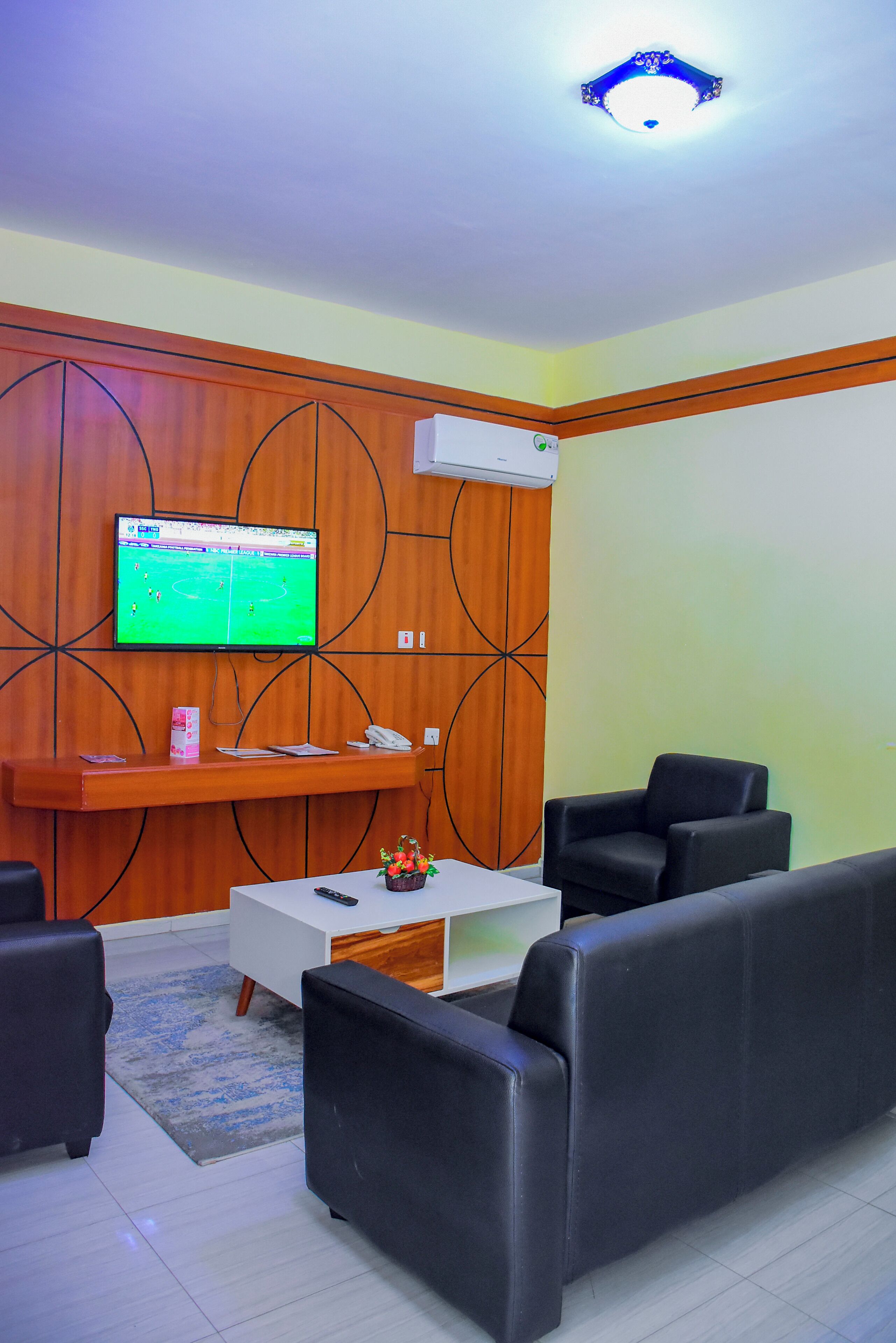 A modern living room with a TV, sofa, coffee table, and a decorative wall panel.