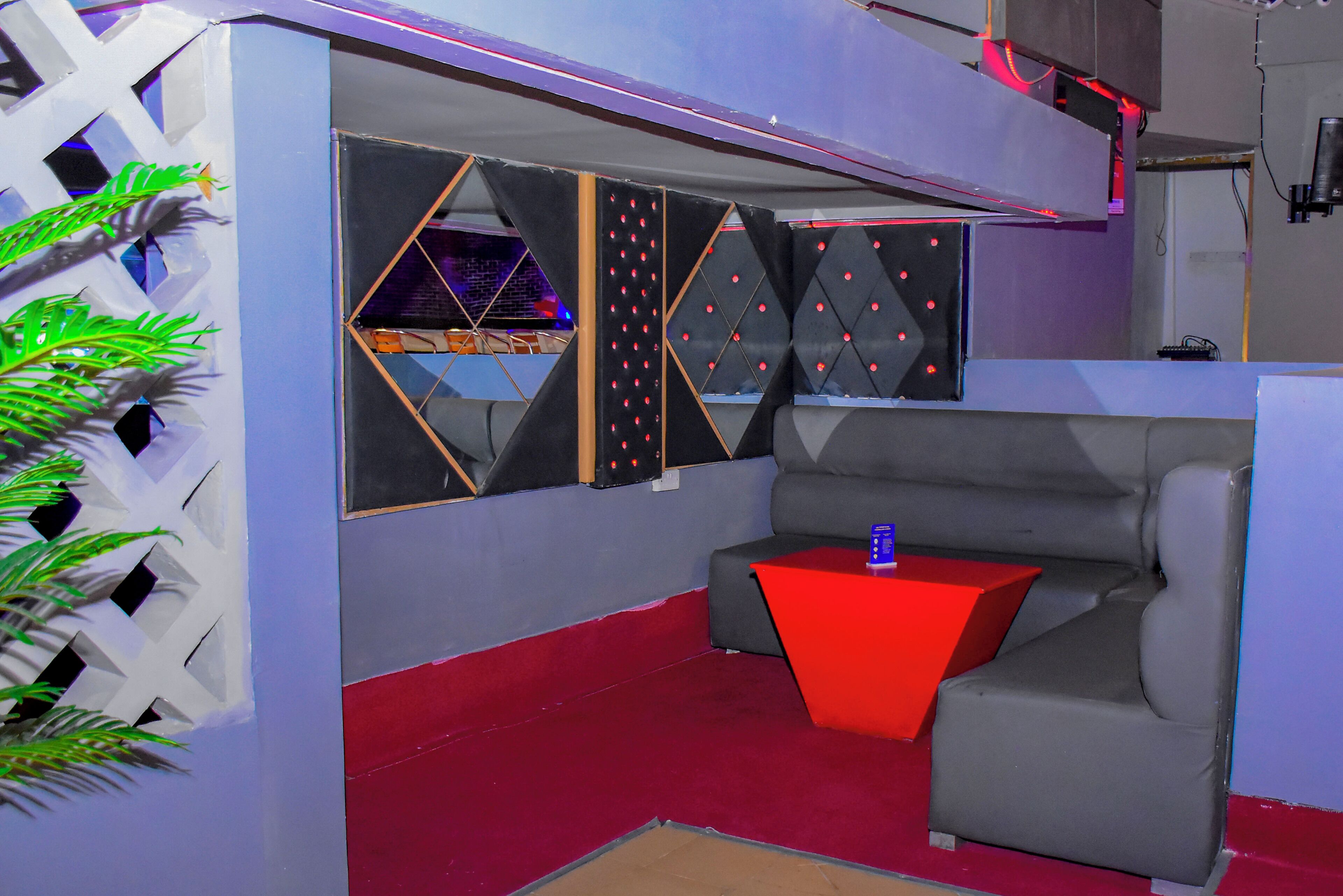 A modern room with a sofa, a red side table, and geometric wall decorations.
