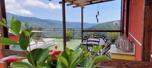 A balcony with a view of mountains, a table with chairs, and potted plants. - Holiday flat with magical terrace (Lucinasco)