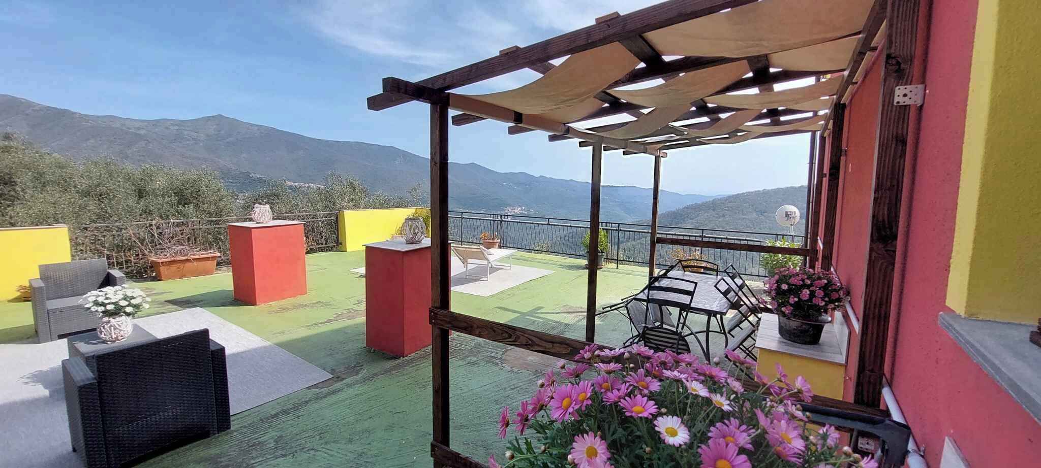 A terrace with outdoor furniture, a pergola, and a view of mountains.
