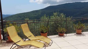Un balcó amb dues cadires de relaxació grogues, plantes en testos i vista a una muntanya.