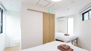 Ett modernt hotellrum med en garderob i trä, en säng med vita sängkläder, ett litet sängbord och ett fönster.