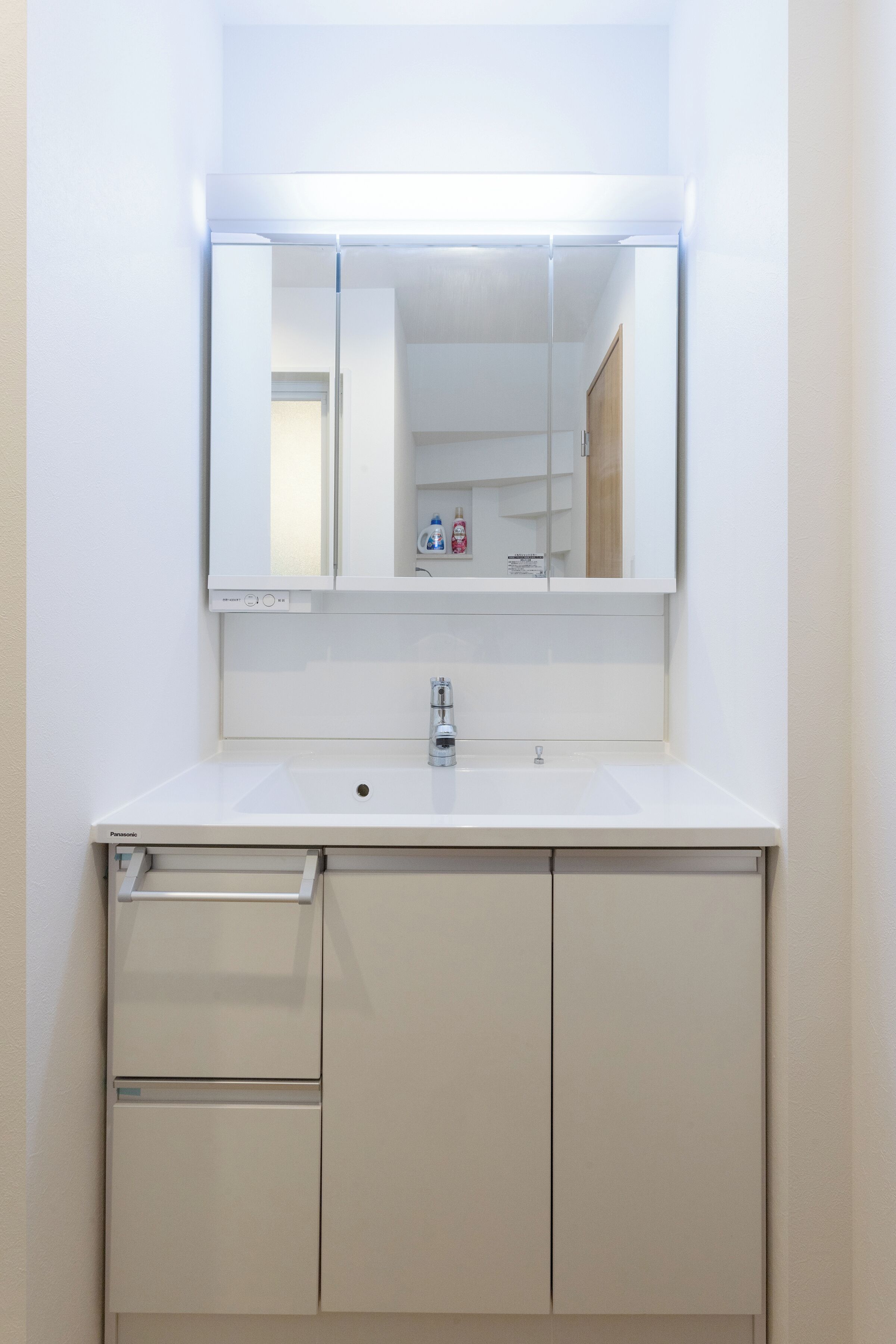 A bathroom with a white sink, a mirror, and a cabinet with drawers.