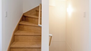 En trätrappa med ett ledstång, vita väggar och en taklampa.