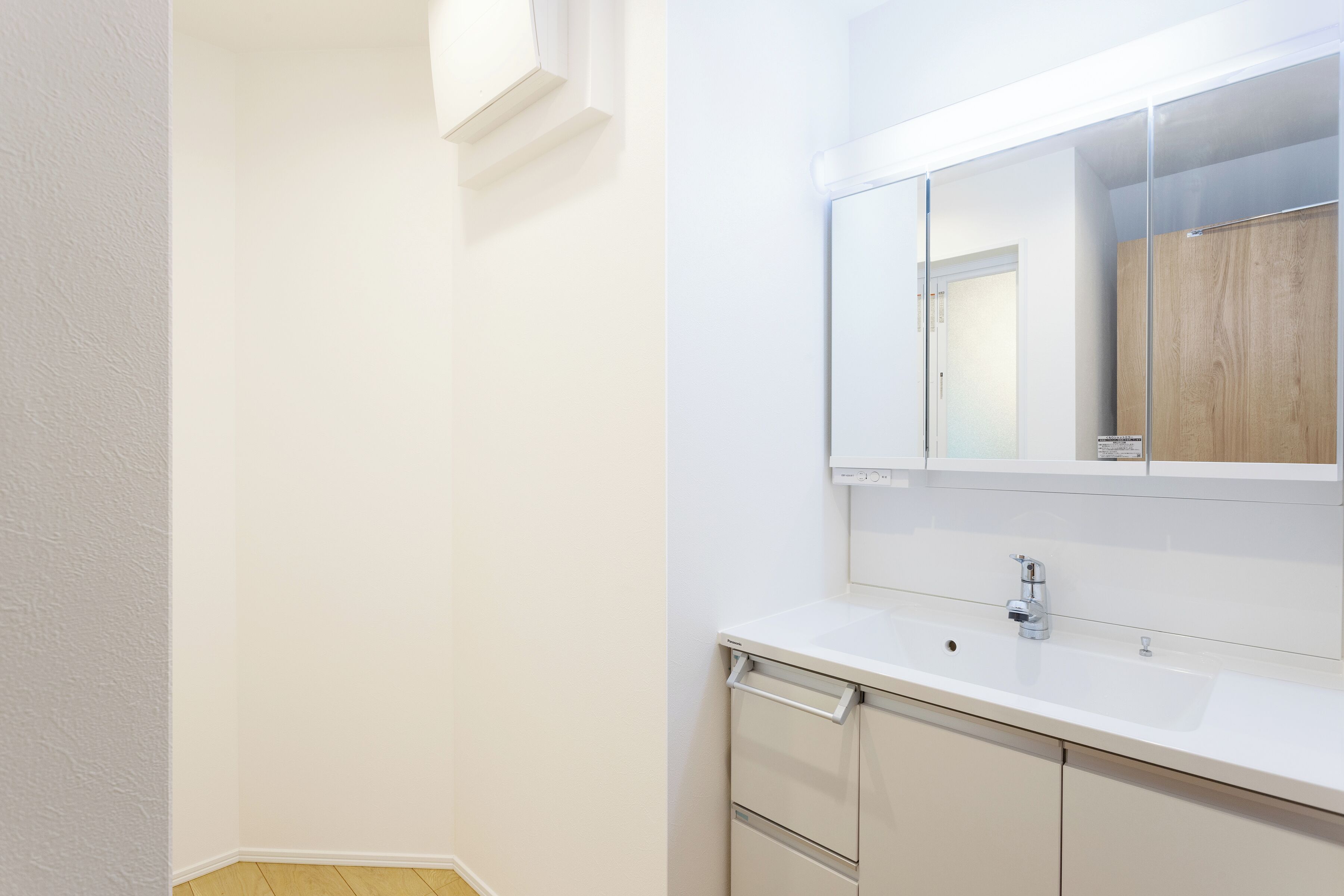 Ein Badezimmer mit einem weißen Waschbecken, einem Spiegel und einem Holzkabinent.