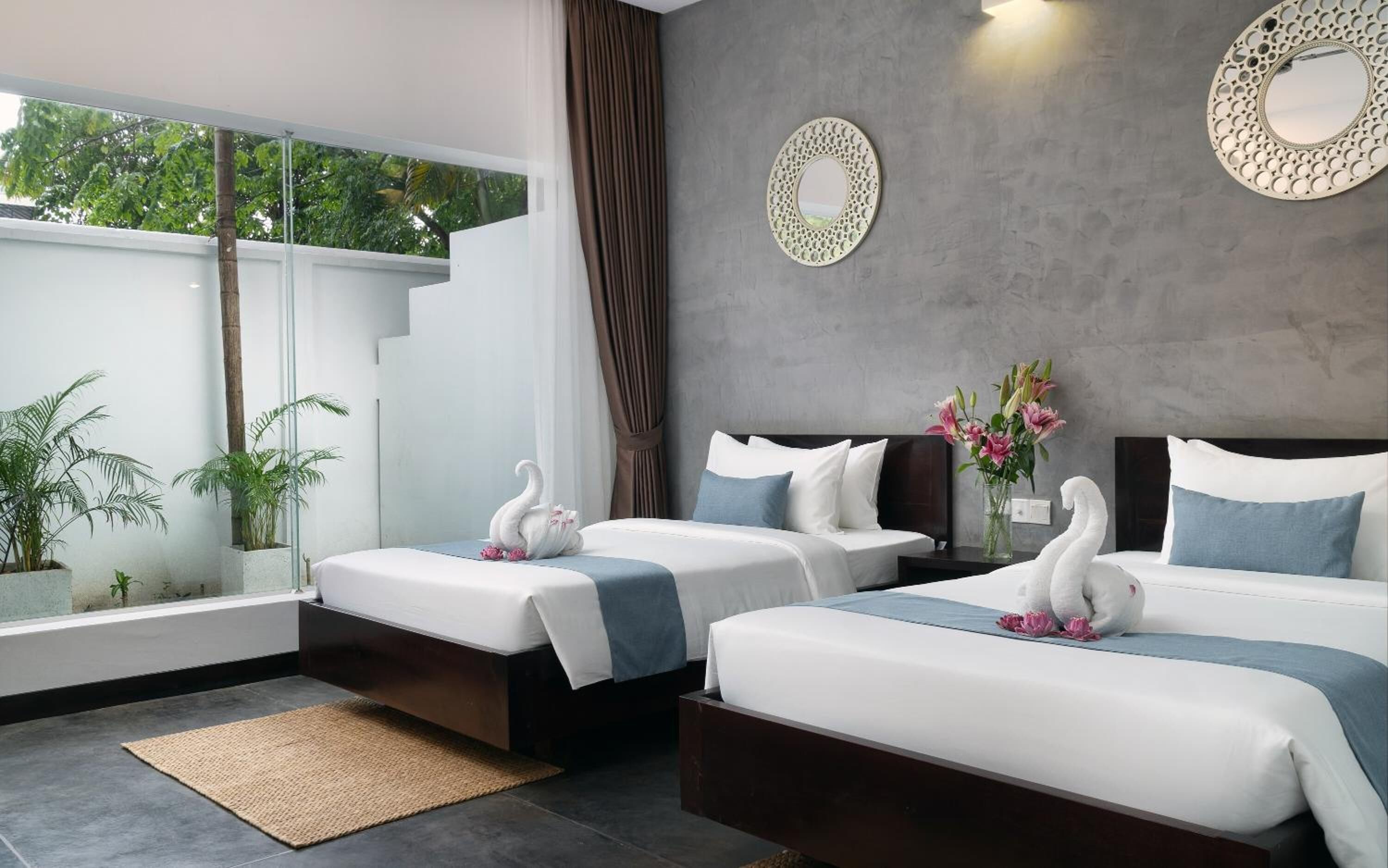 Una habitación de hotel moderna con dos camas, un ventanal grande y almohadas decorativas con forma de cisne.