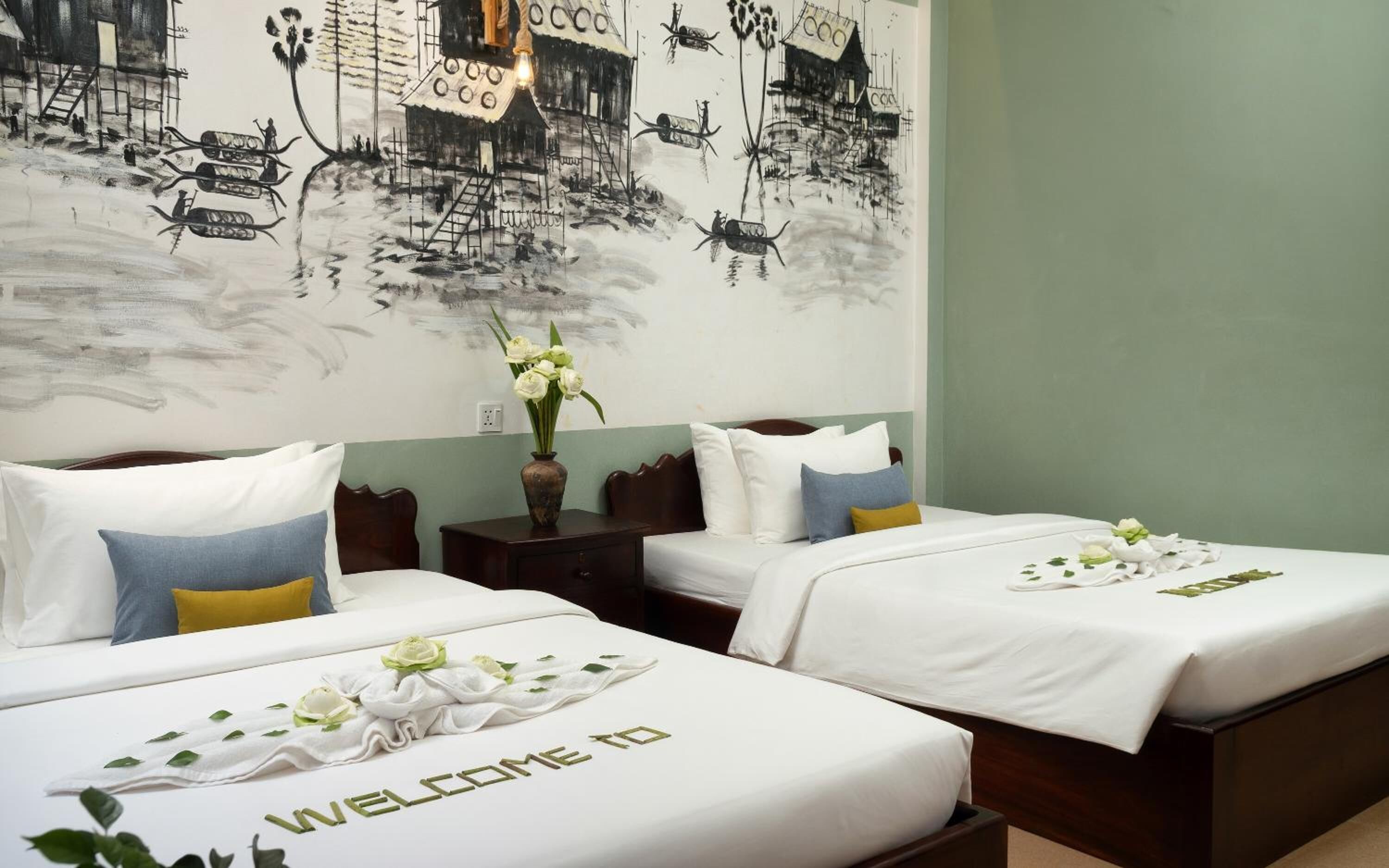 A hotel room with two beds, a nightstand, a wall mural, and a vase with flowers.