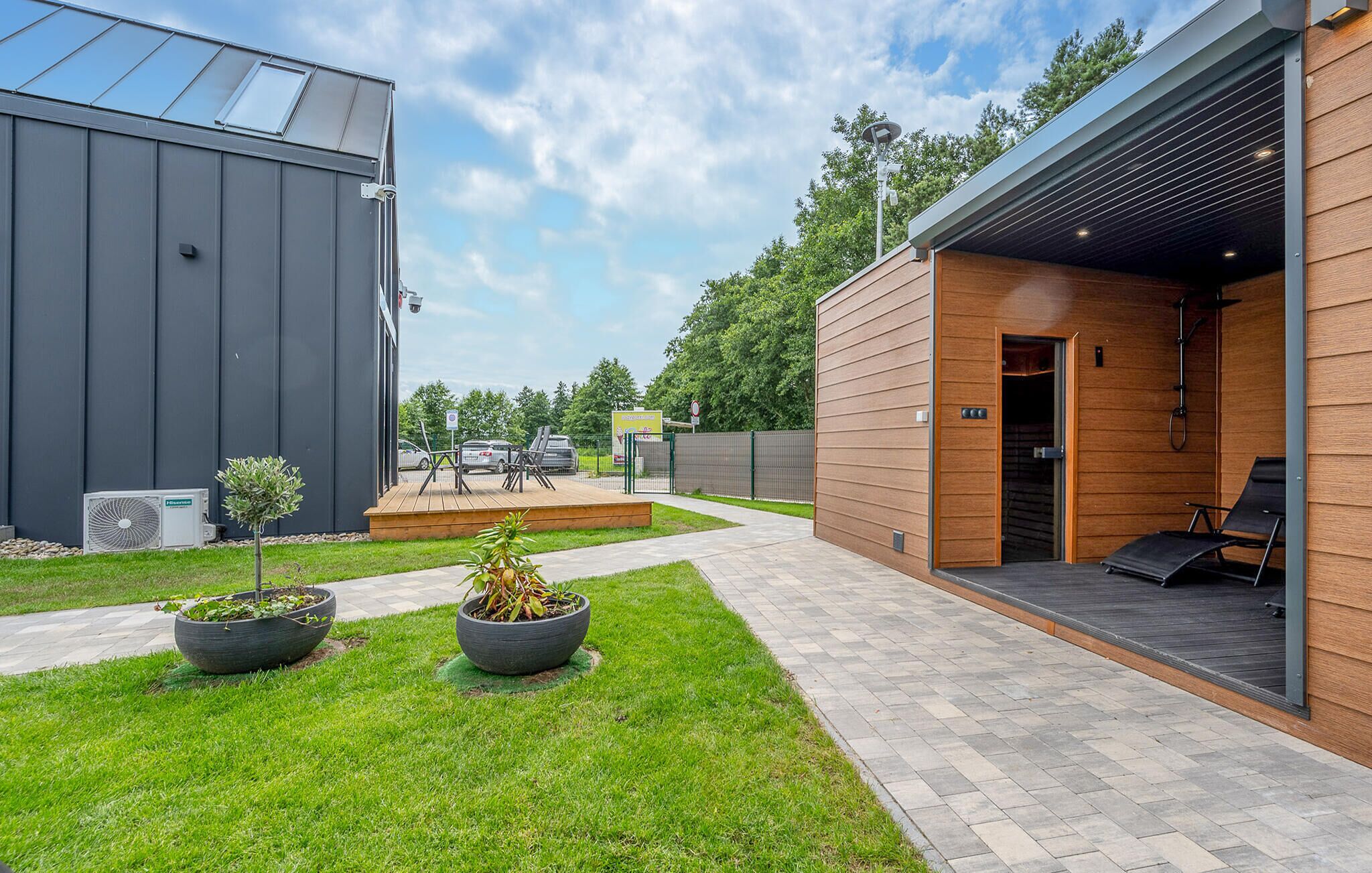 A modern building with a patio area, outdoor seating, and a large air conditioning unit.