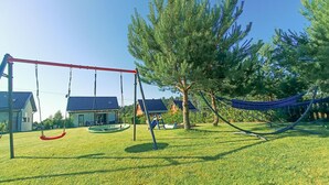 Un’area giochi con altalene e un’amaca, circondata da erba e alberi.