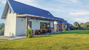 Una casa moderna con tetto spiovente, un portico coperto con mobili da esterno e un prato curato.