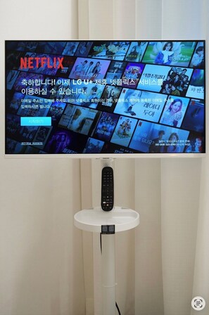 Ein an der Wand befestigtes Fernsehgerät zeigt eine Netflix-Oberfläche mit verschiedenen Vorschaubildern von Sendungen.