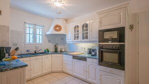 Une cuisine avec des meubles blancs, un four Bosch et un four à micro-ondes Siemens.
