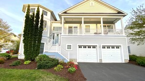 A two-story house with a front porch, a garage, and a well-maintained garden. - Spacious Luxury Home in Waterfront Resort w/ Pools (Berlin)