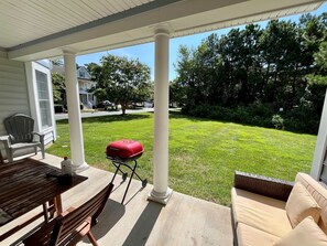 A covered patio with a grill, a table, and a sofa. - Spacious Luxury Home in Waterfront Resort w/ Pools (Berlin)
