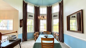 A dining room with a table set for six, a chandelier, patterned curtains, and a large mirror on the wall. - Spacious Luxury Home in Waterfront Resort w/ Pools (Berlin)