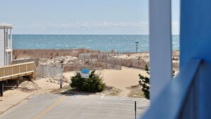 Vista sulla spiaggia con una passerella di legno, un'area recintata e un parcheggio.